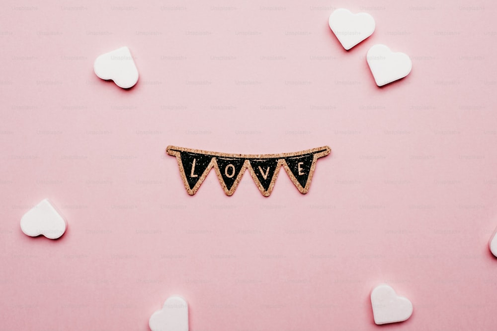 a wooden sign that says love on a pink background