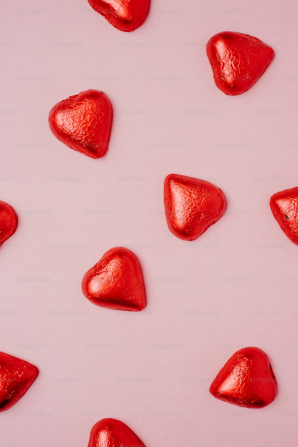 a group of red heart shaped candies on a pink background