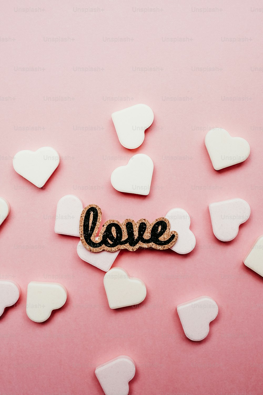 La parola amore scritta con un blocco di legno circondato da cuori bianchi