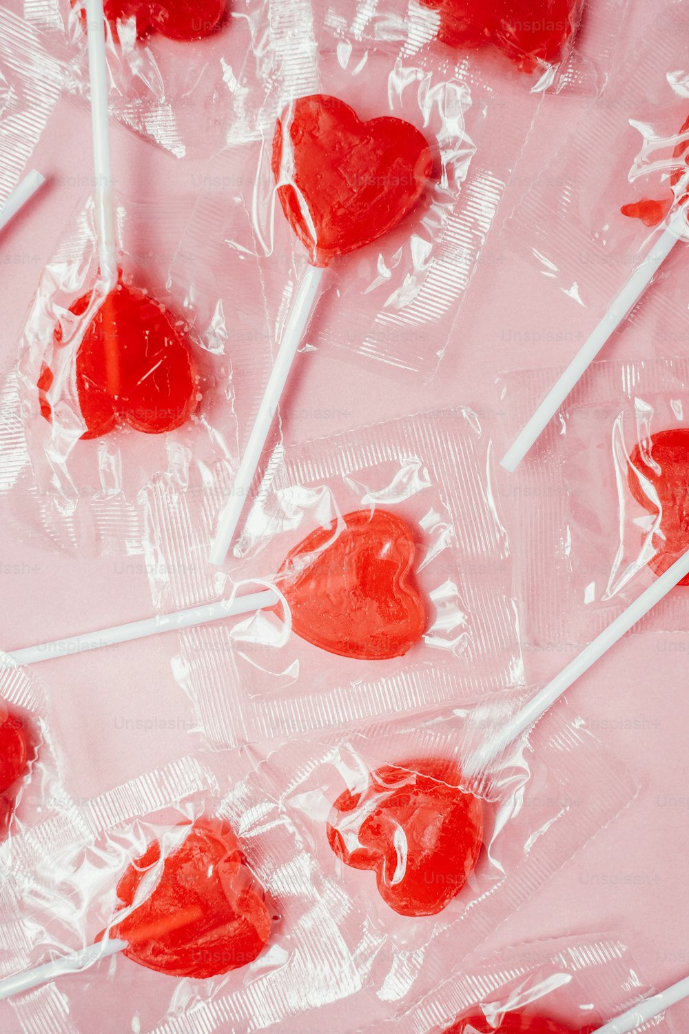 a bunch of heart shaped lollipops on a pink background