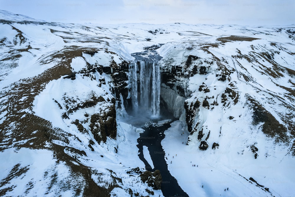 a large waterfall in the middle of a snowy mountain
