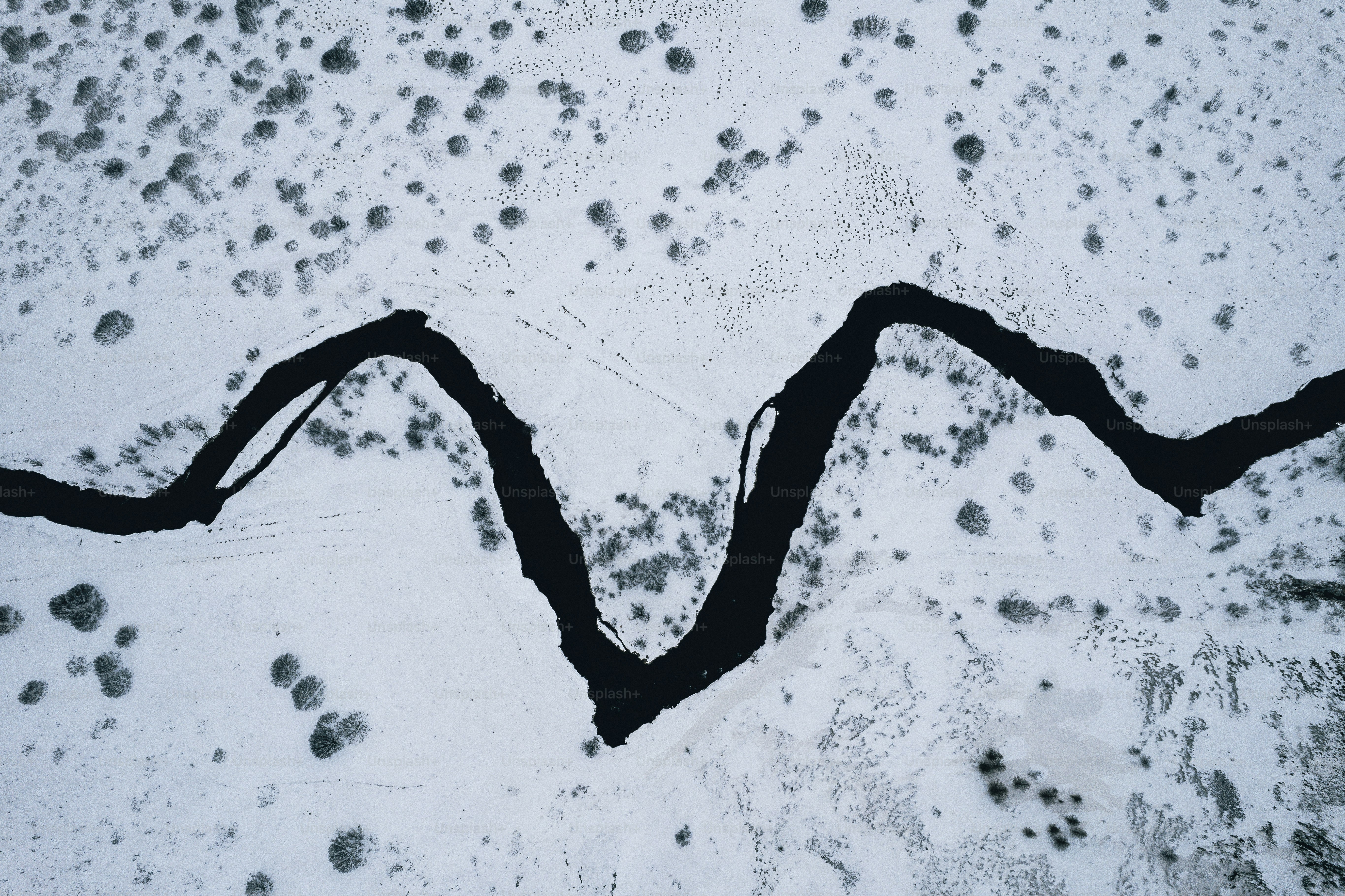 an aerial view of a river in the snow