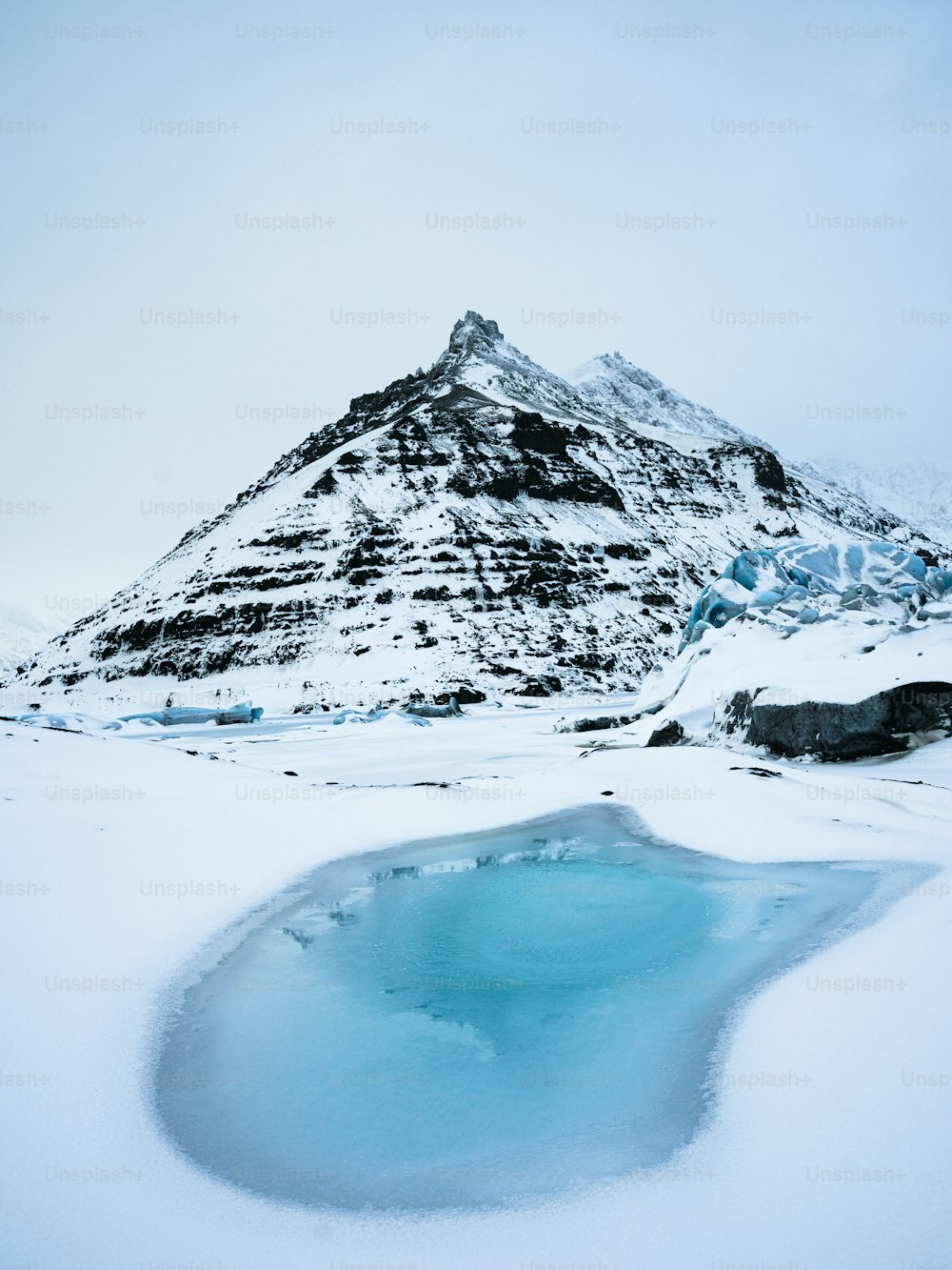 a mountain with a pool of water in the snow