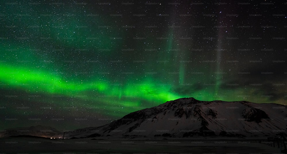 a green and purple aurora bore over a snowy mountain