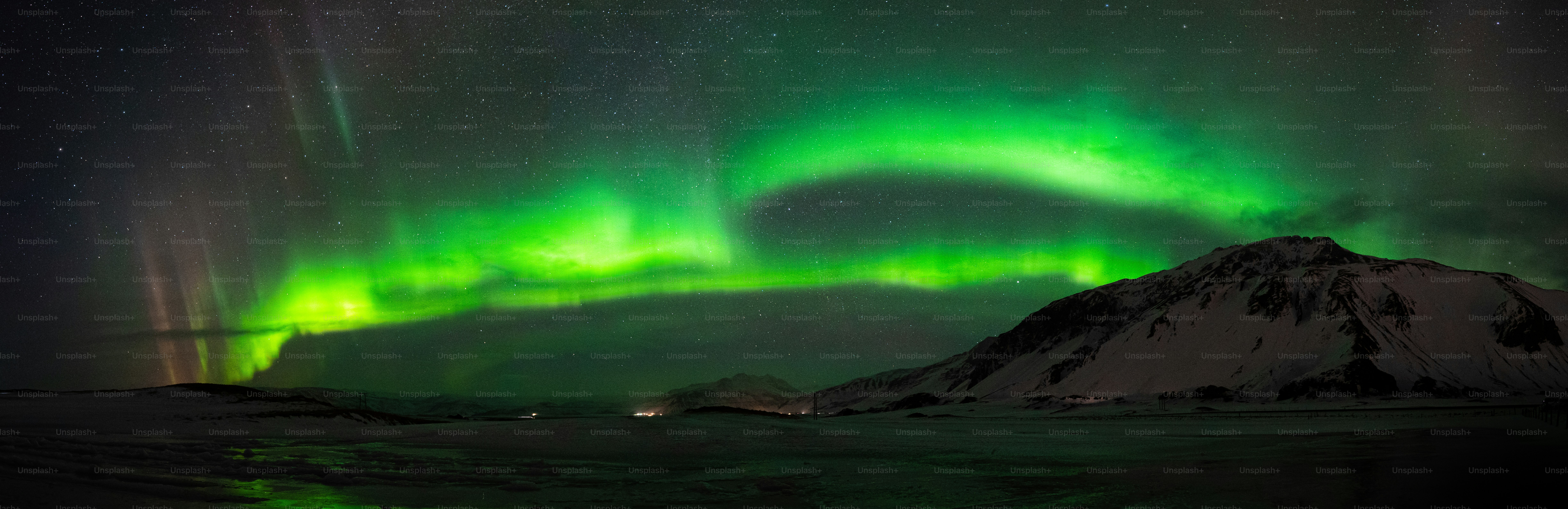a green and purple aurora bore above a snowy mountain