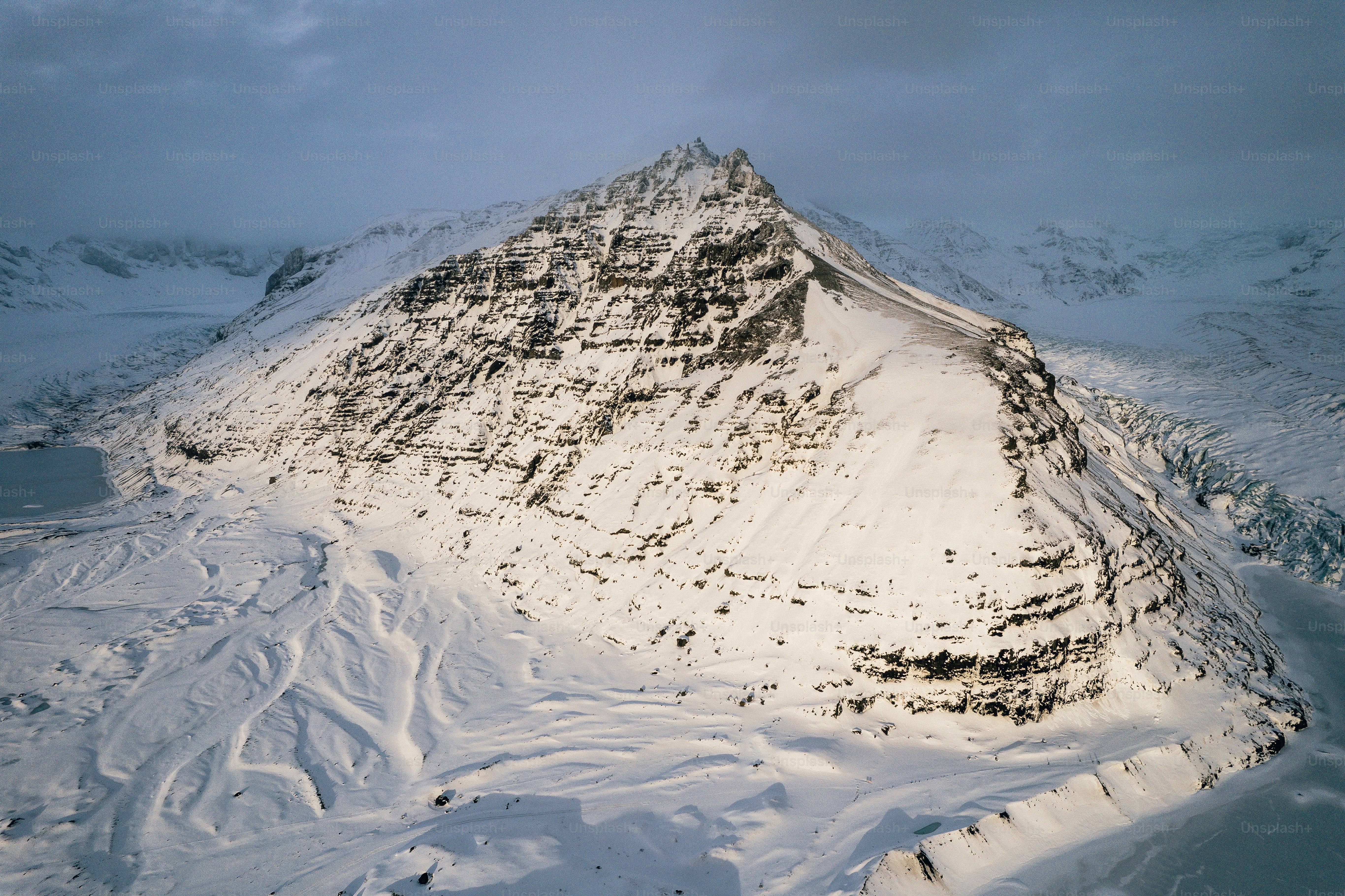 a mountain covered in snow under a cloudy sky