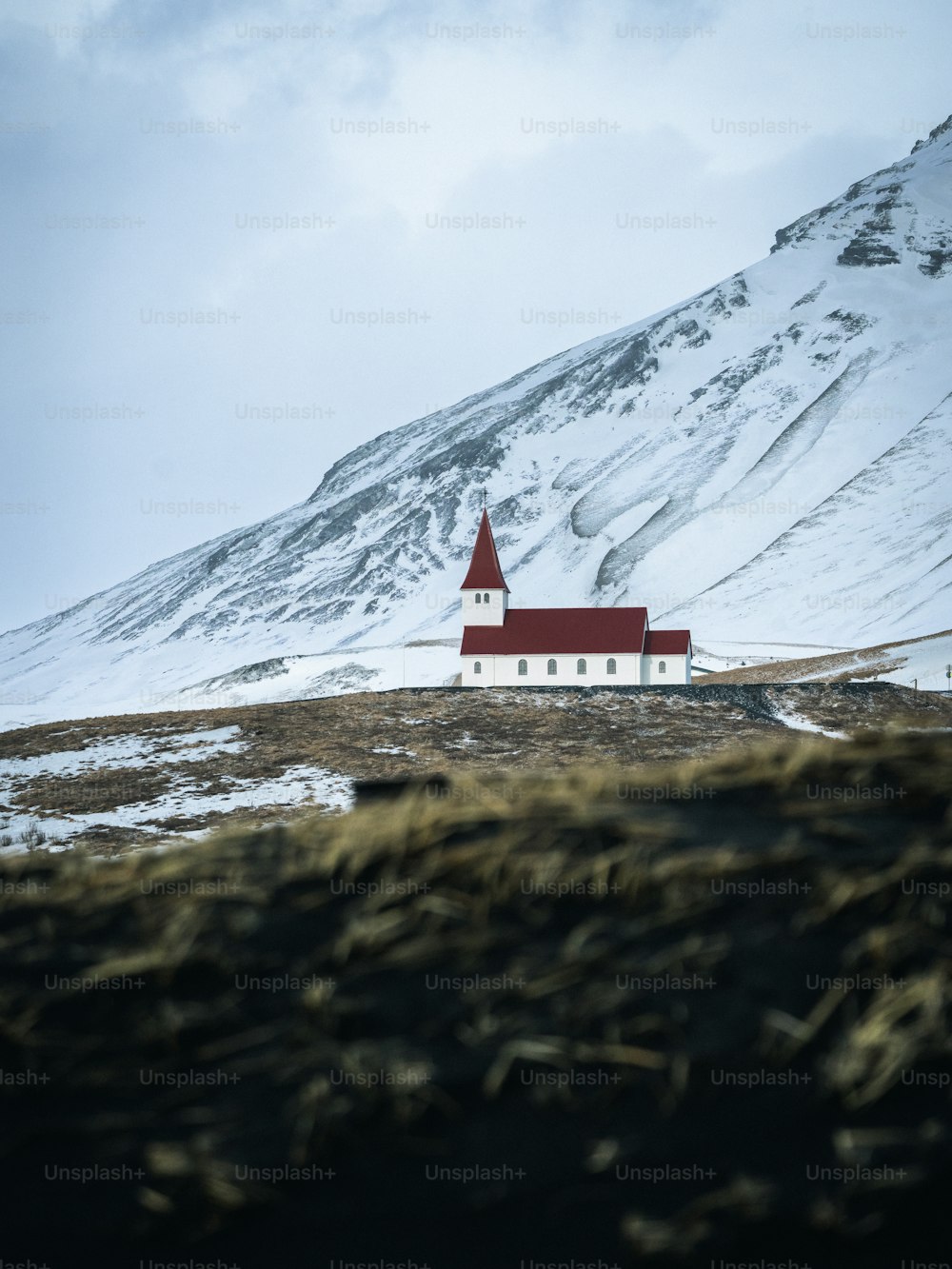 a red and white church sitting on top of a snow covered hill