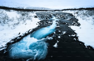 a stream of water running through a snow covered landscape