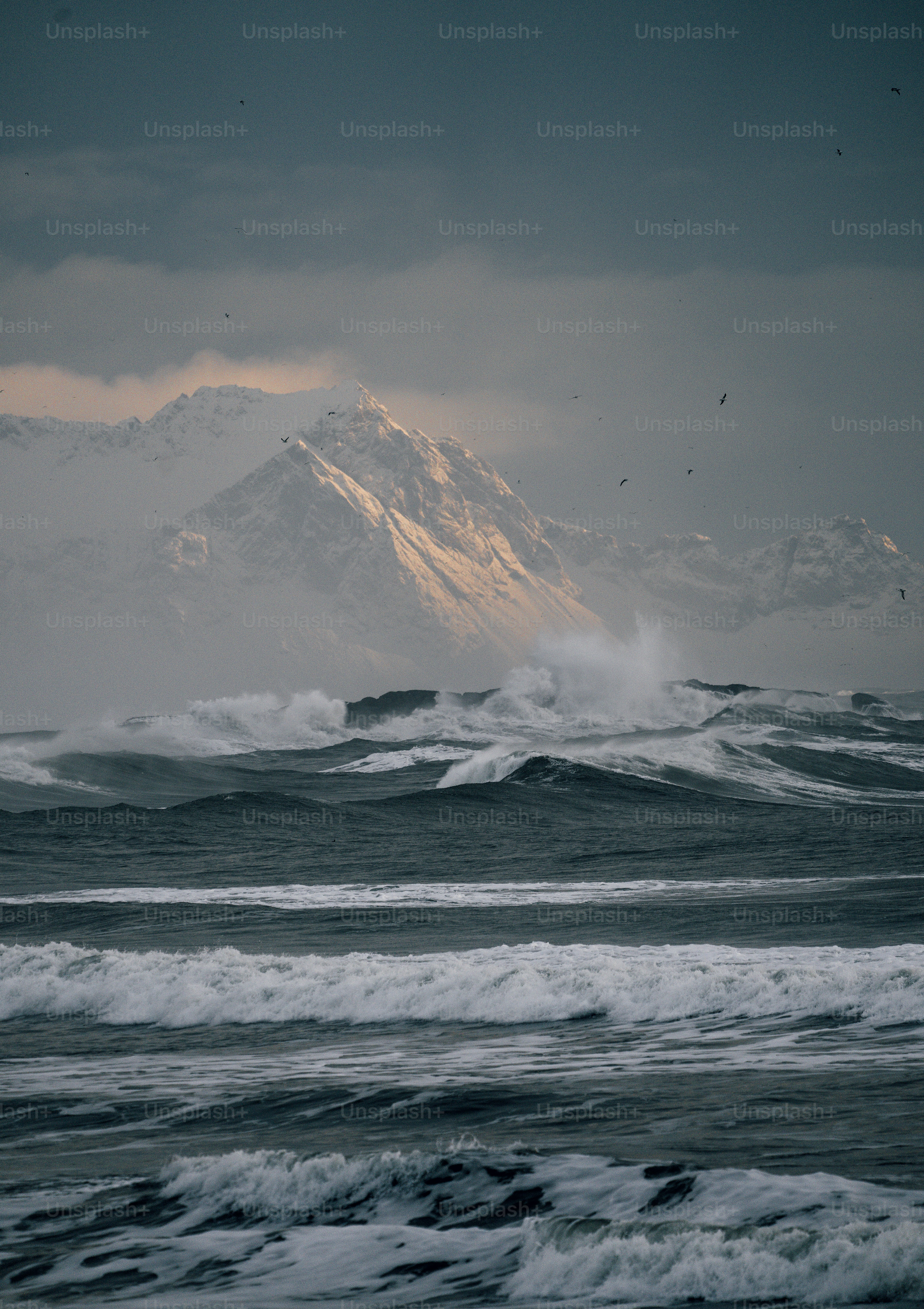 a large snow covered mountain towering over a body of water