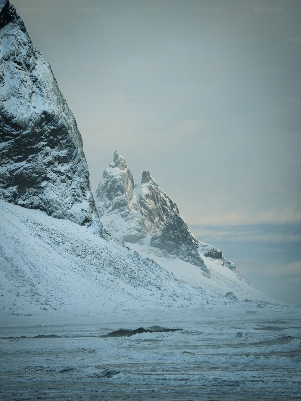 a mountain covered in snow next to a body of water