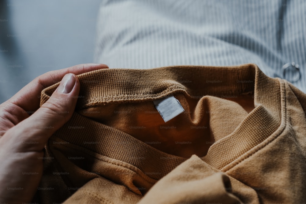 a person holding a brown shirt with a tag on it