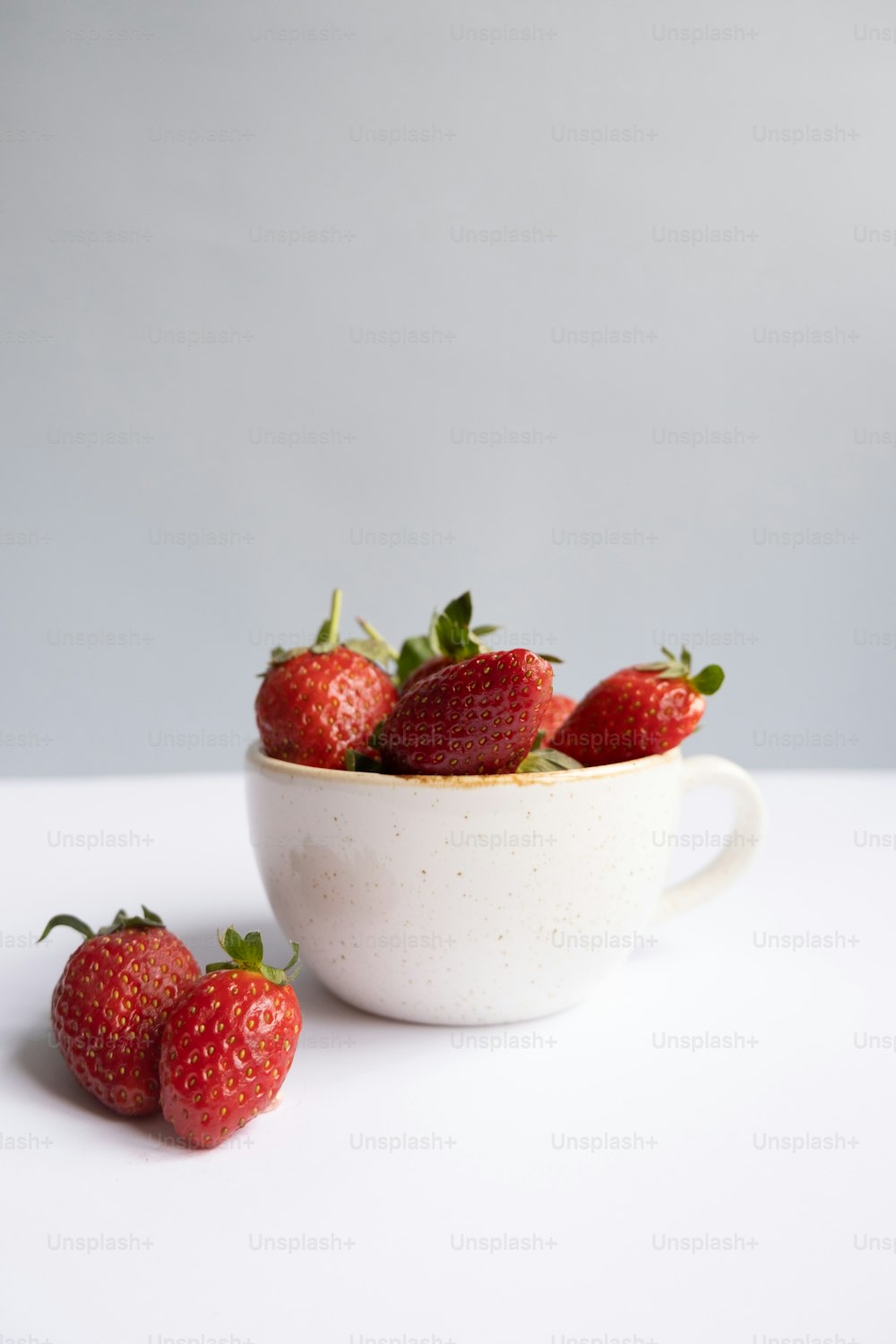 a white bowl filled with strawberries on top of a table