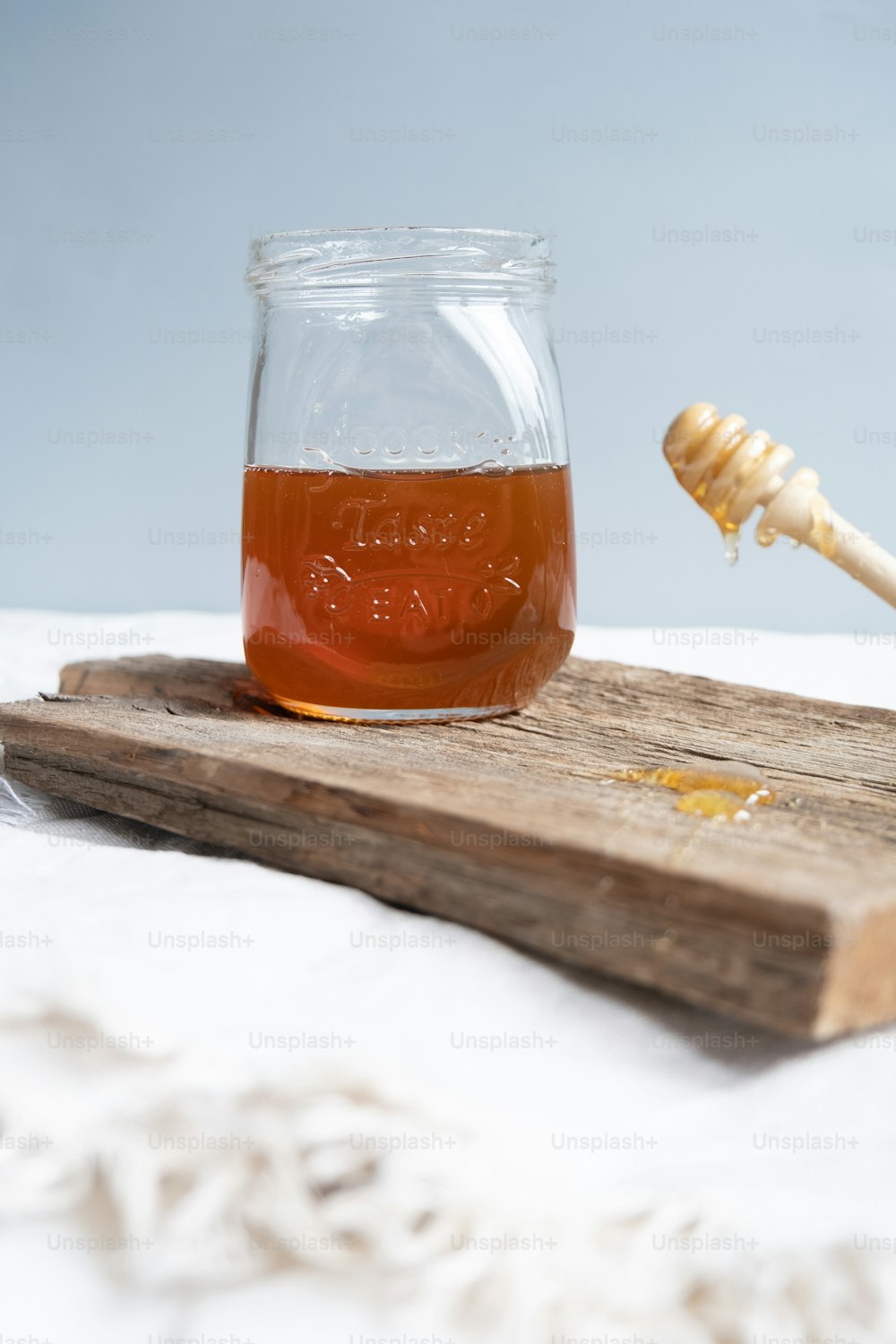 um frasco de mel sentado em uma bandeja de madeira