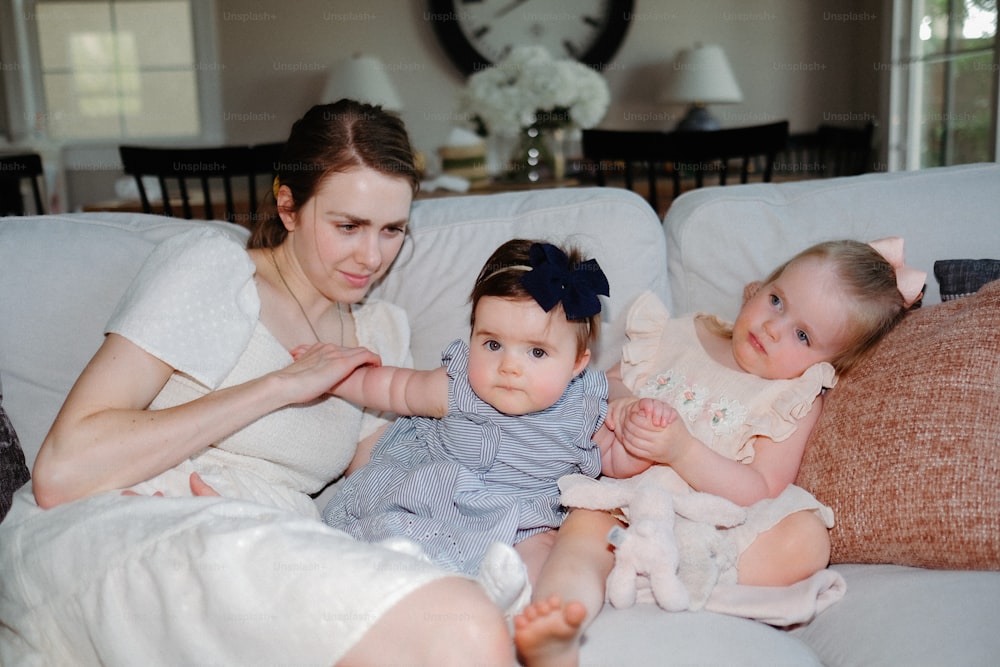 a woman sitting on a couch with two babies