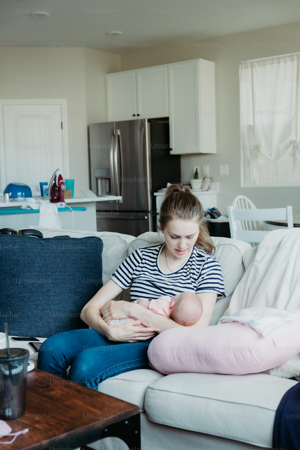 Una mujer sentada en un sofá sosteniendo a un bebé