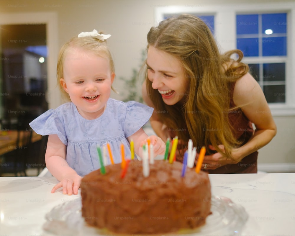 a woman and a little girl looking at a cake with candles