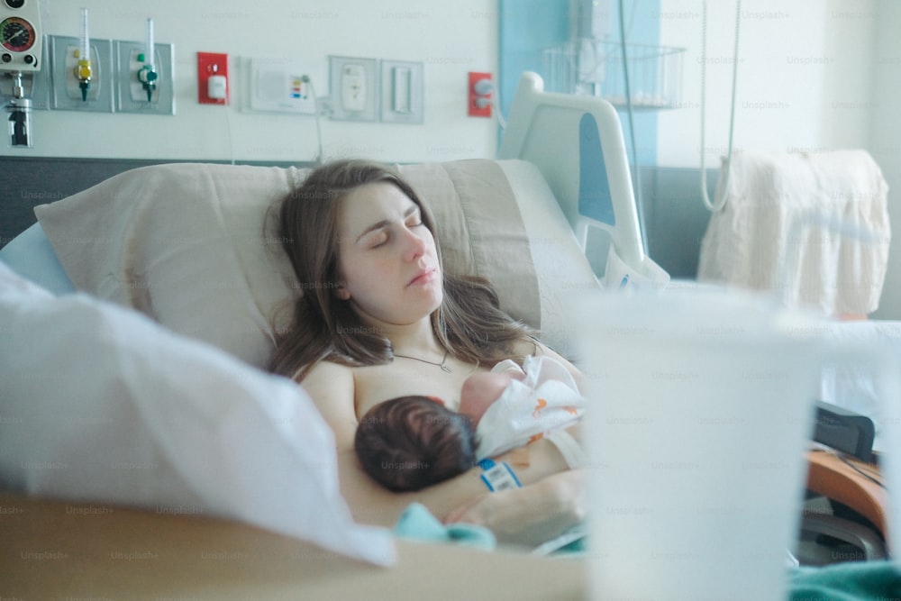 uma mulher deitada em uma cama de hospital segurando um bebê
