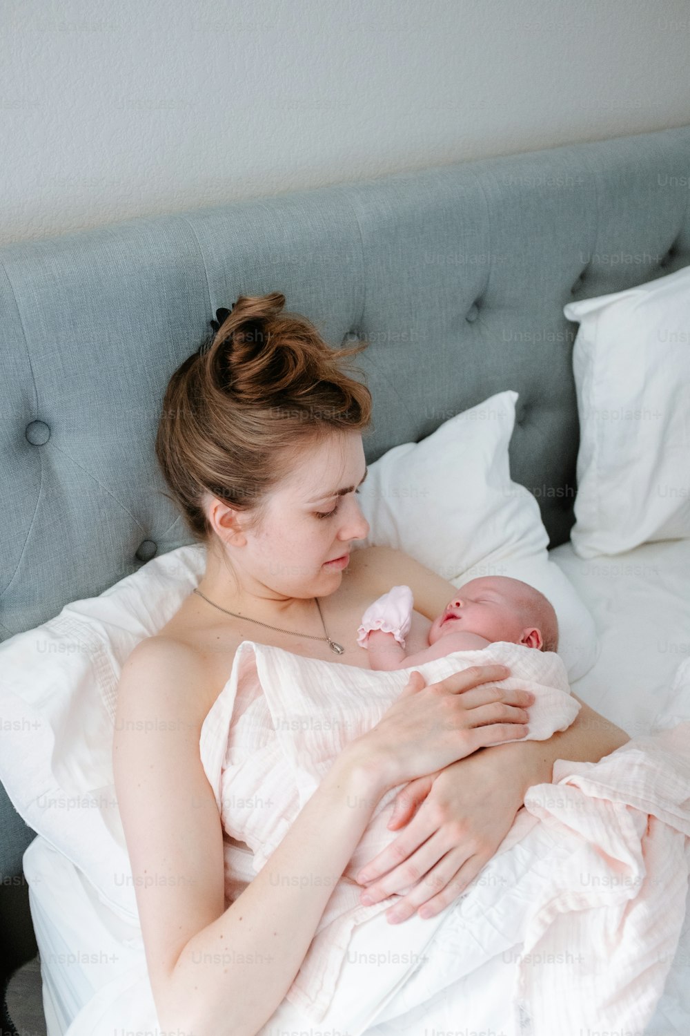ベッドの上で赤ん坊を腕に抱く女性
