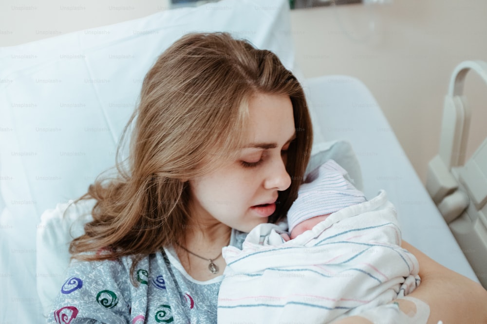 病院のベッドで赤ちゃんを抱く女性