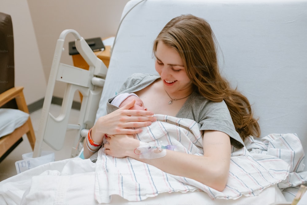 uma mulher que segura um bebê em uma cama de hospital
