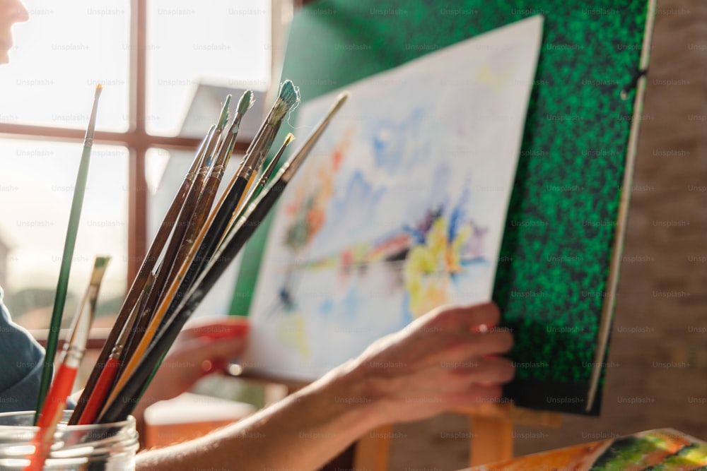 a woman is holding a paintbrush and painting a picture