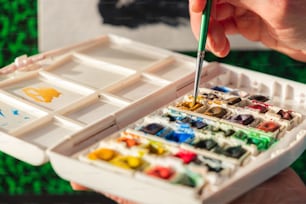 a person holding a paintbrush and a box of paint