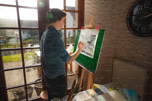 a woman standing in front of a window holding a paintbrush