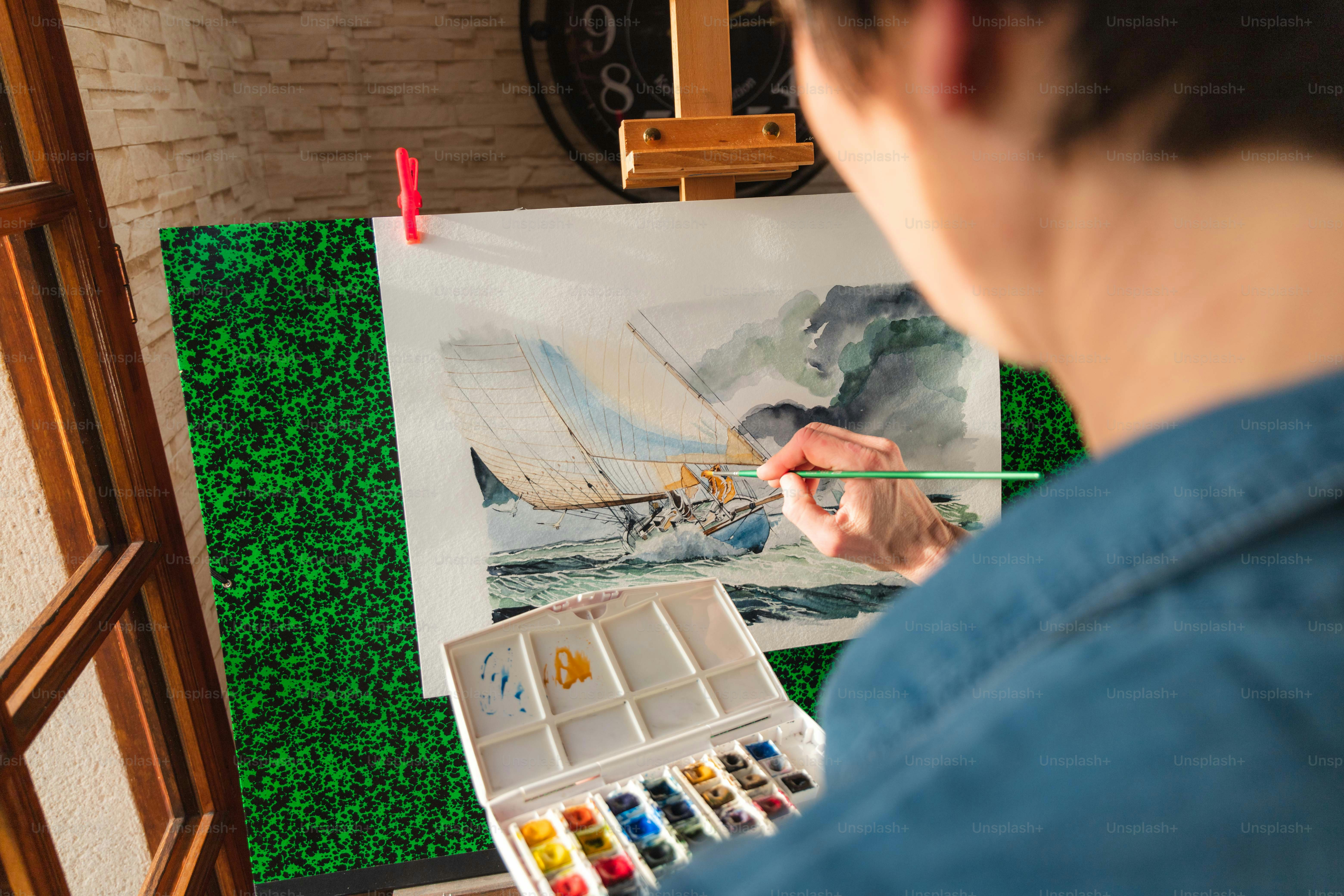 Un hombre está pintando un cuadro de un velero