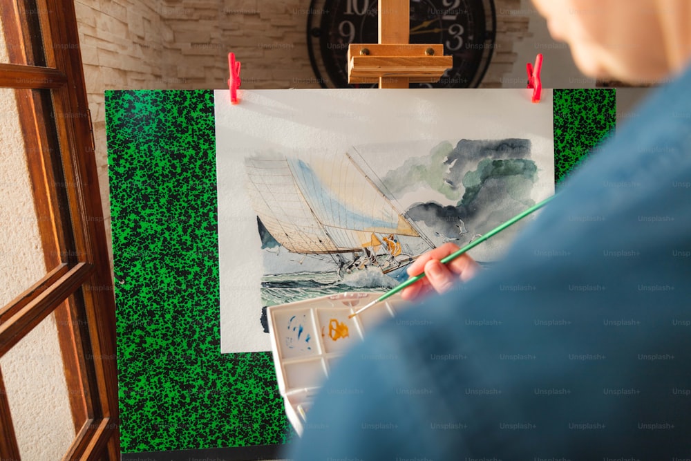a person holding a paintbrush in front of a painting