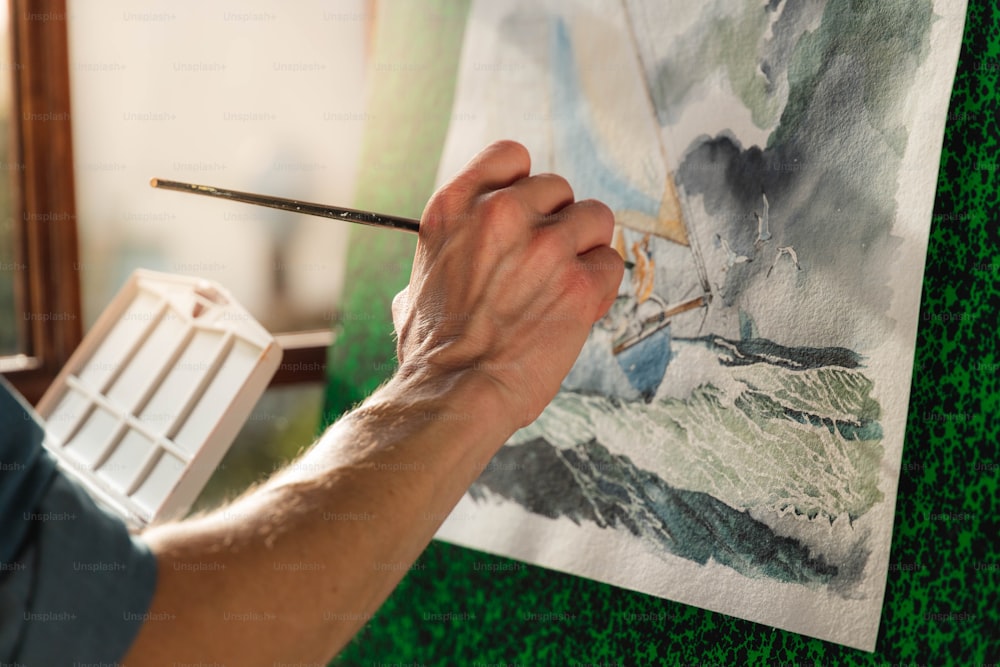 Un uomo sta dipingendo un quadro con un pennello