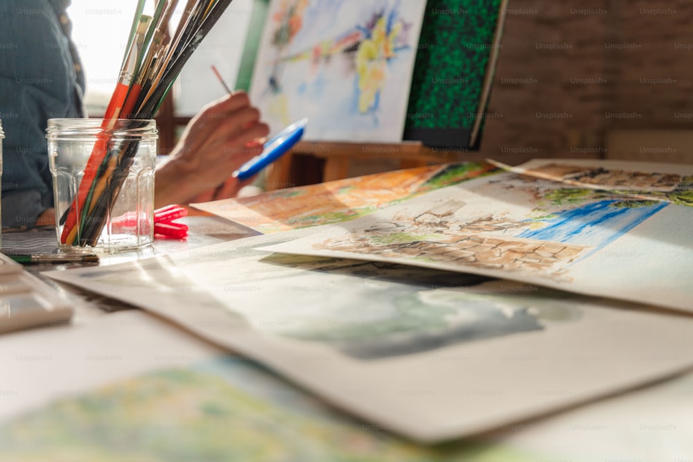 a person sitting at a table with art supplies