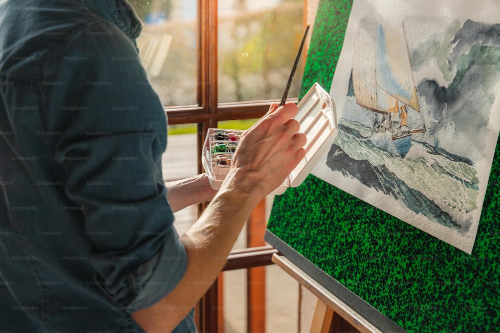 Un uomo sta dipingendo un quadro su un cavalletto
