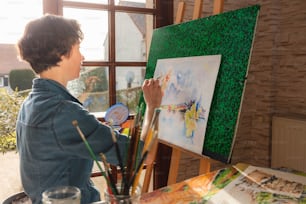 Un niño está pintando un cuadro en un caballete