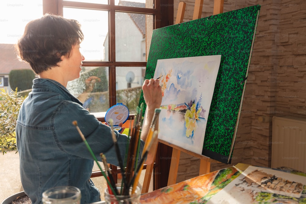 a boy is painting a picture on a easel