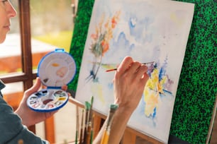 Una mujer está pintando sobre un lienzo con un pincel