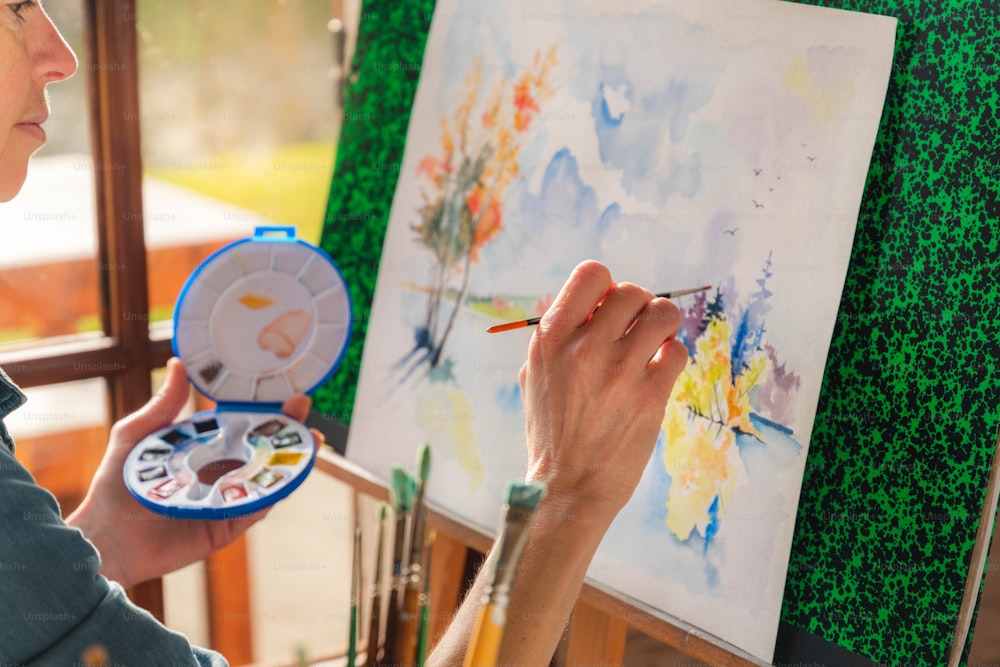 女性がブラシでキャンバスに絵を描いている