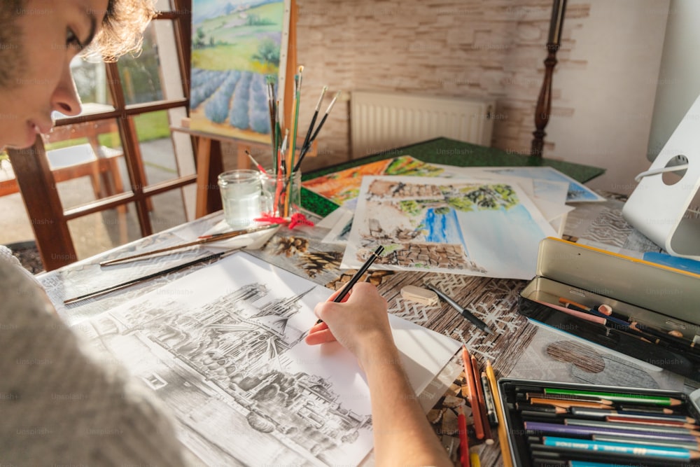 a man sitting at a table with art supplies