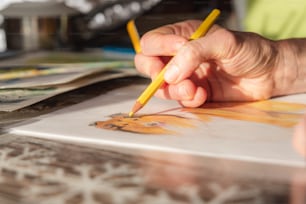 uma pessoa segurando um lápis e desenhando em um pedaço de papel
