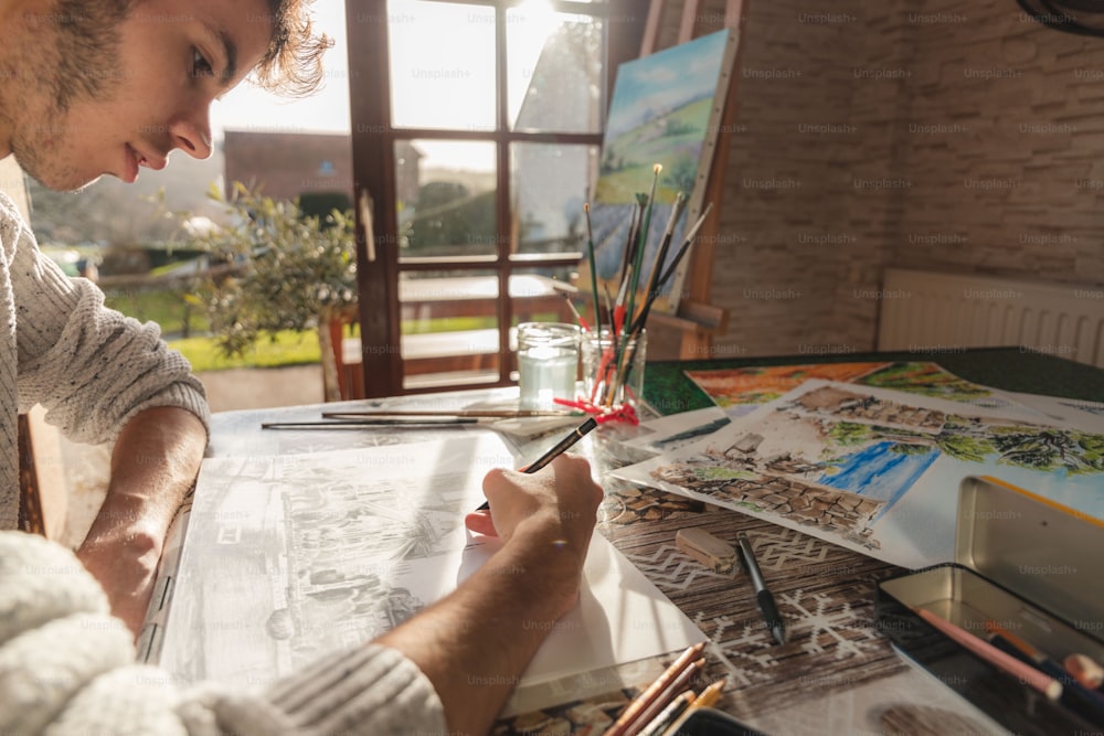 a man sitting at a table drawing on a piece of paper