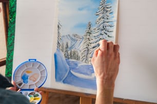 uma pessoa pintando uma imagem de uma paisagem nevada