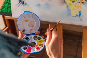 a person holding a paintbrush and a palette