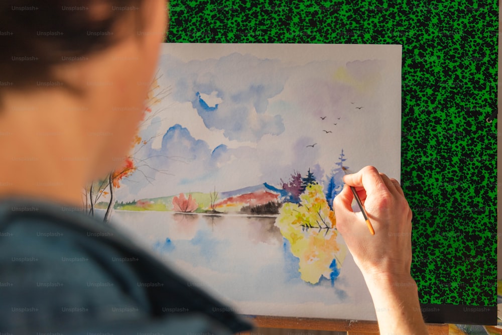 Una mujer está pintando un paisaje con acuarelas