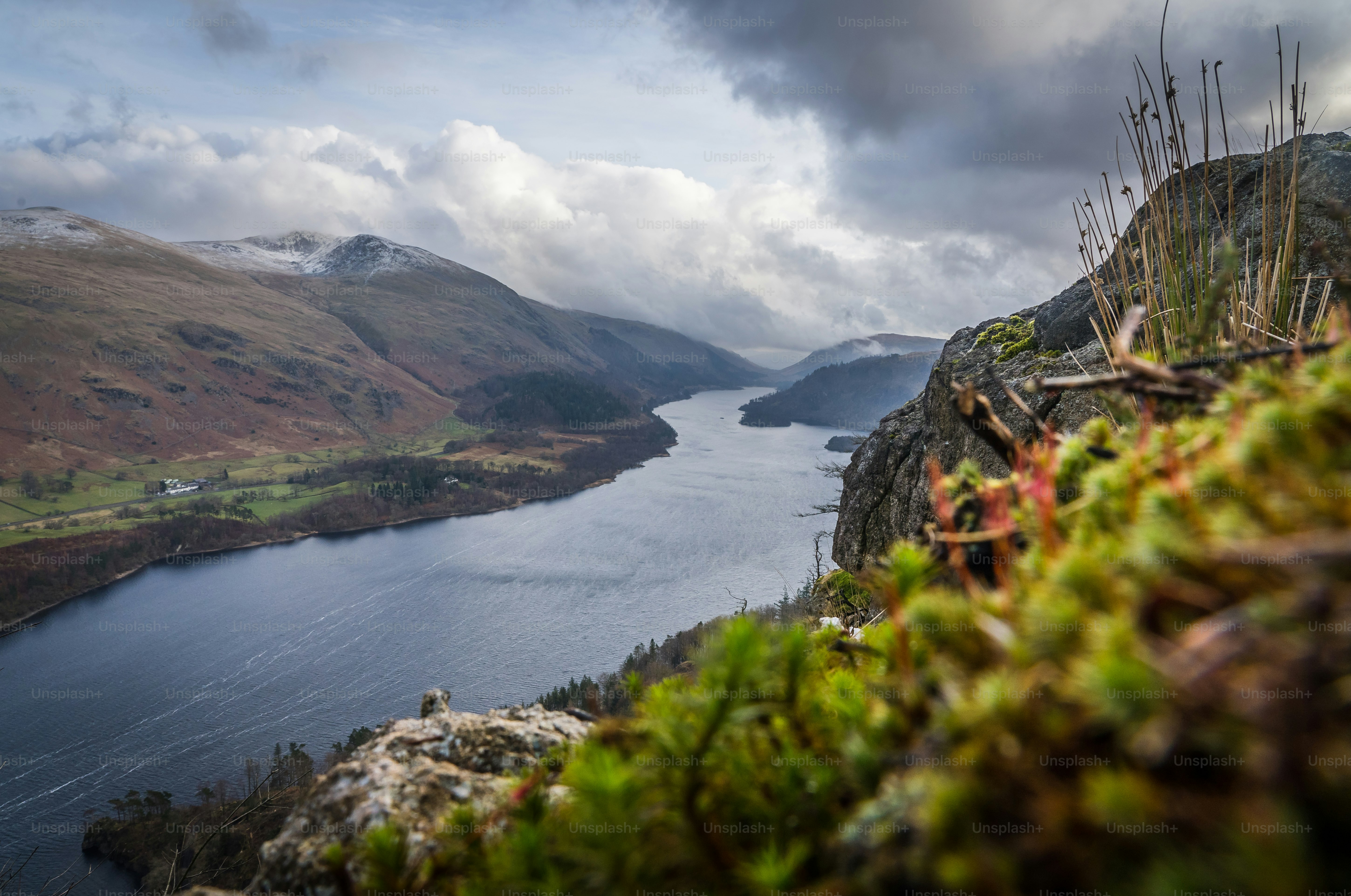 a body of water surrounded by mountains under a cloudy sky