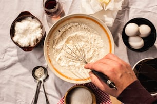 a person mixing ingredients in a bowl on a table