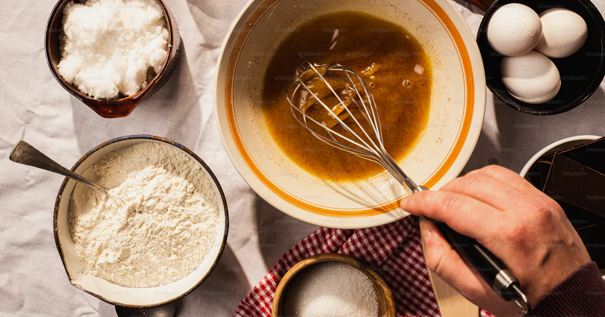 A person mixing ingredients in a bowl on a table photo – Chocolate chip ...
