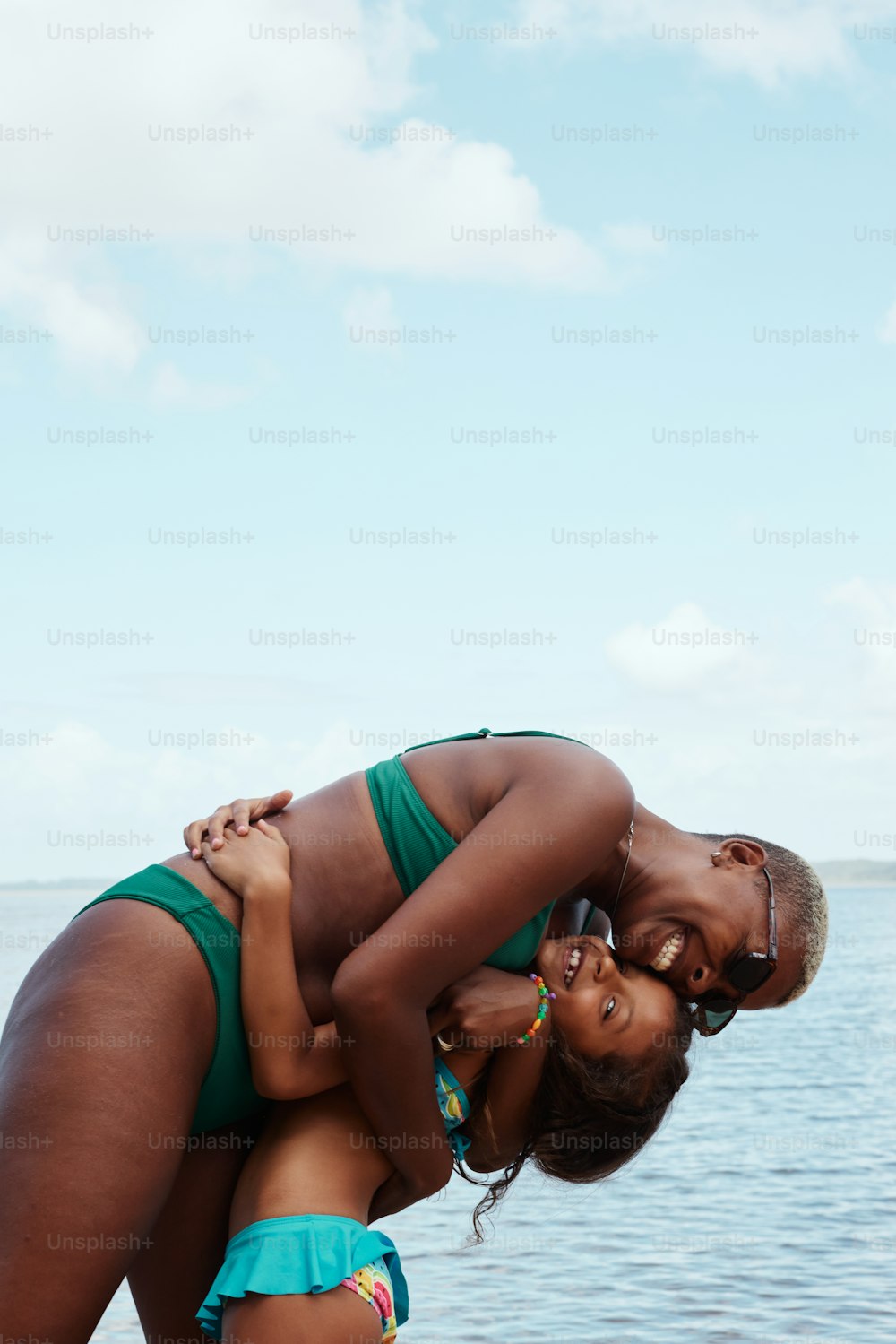 uma mulher em um biquíni segurando uma criança na praia