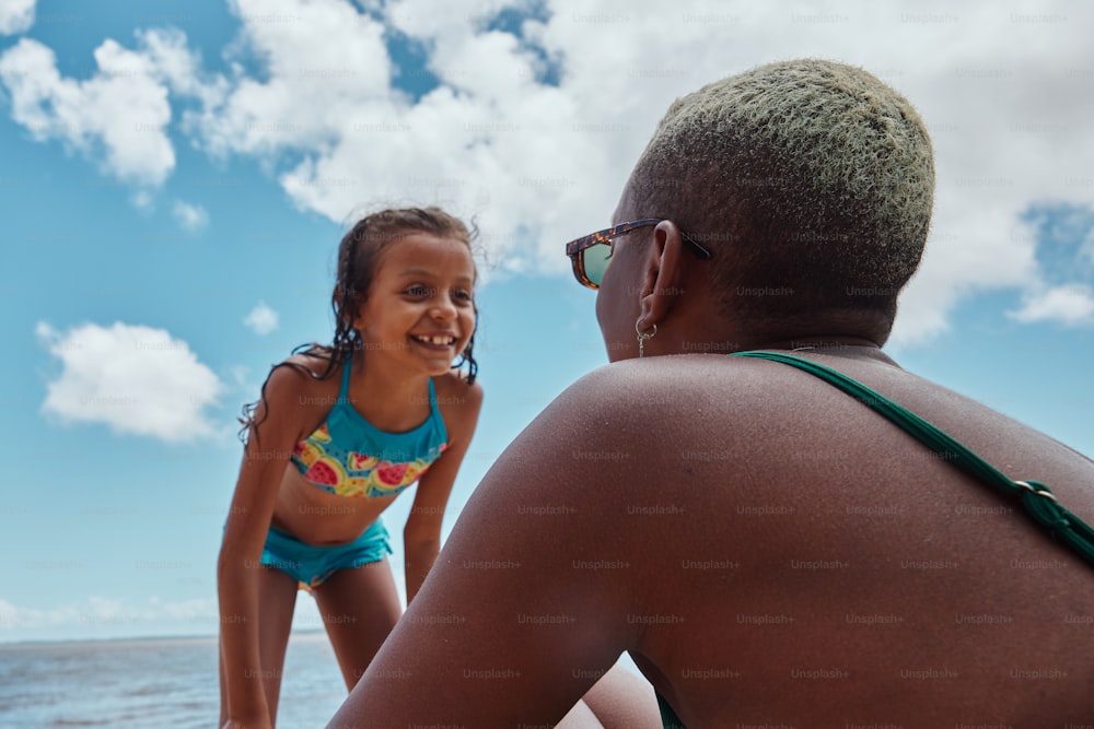 a woman standing next to a little girl on a beach