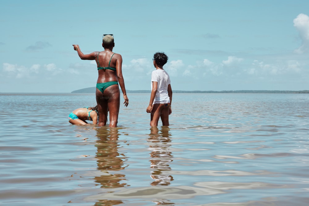 a woman in a bikini standing next to a man in the water