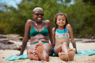 a woman and a little girl sitting on a beach