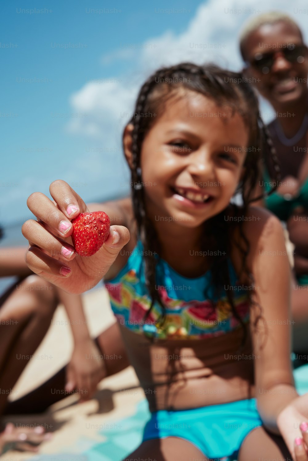 a little girl holding a strawberry in her hand
